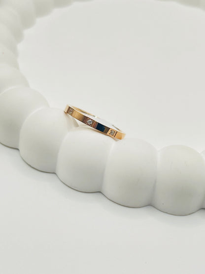Rose Gold ring with embedded stones on a white ceramic surface