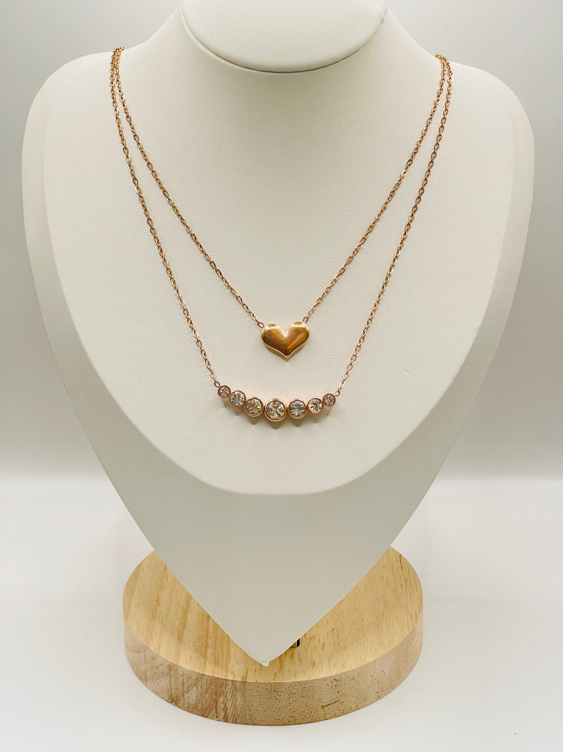 Gold necklace with a heart pendant on a white mannequin bust.