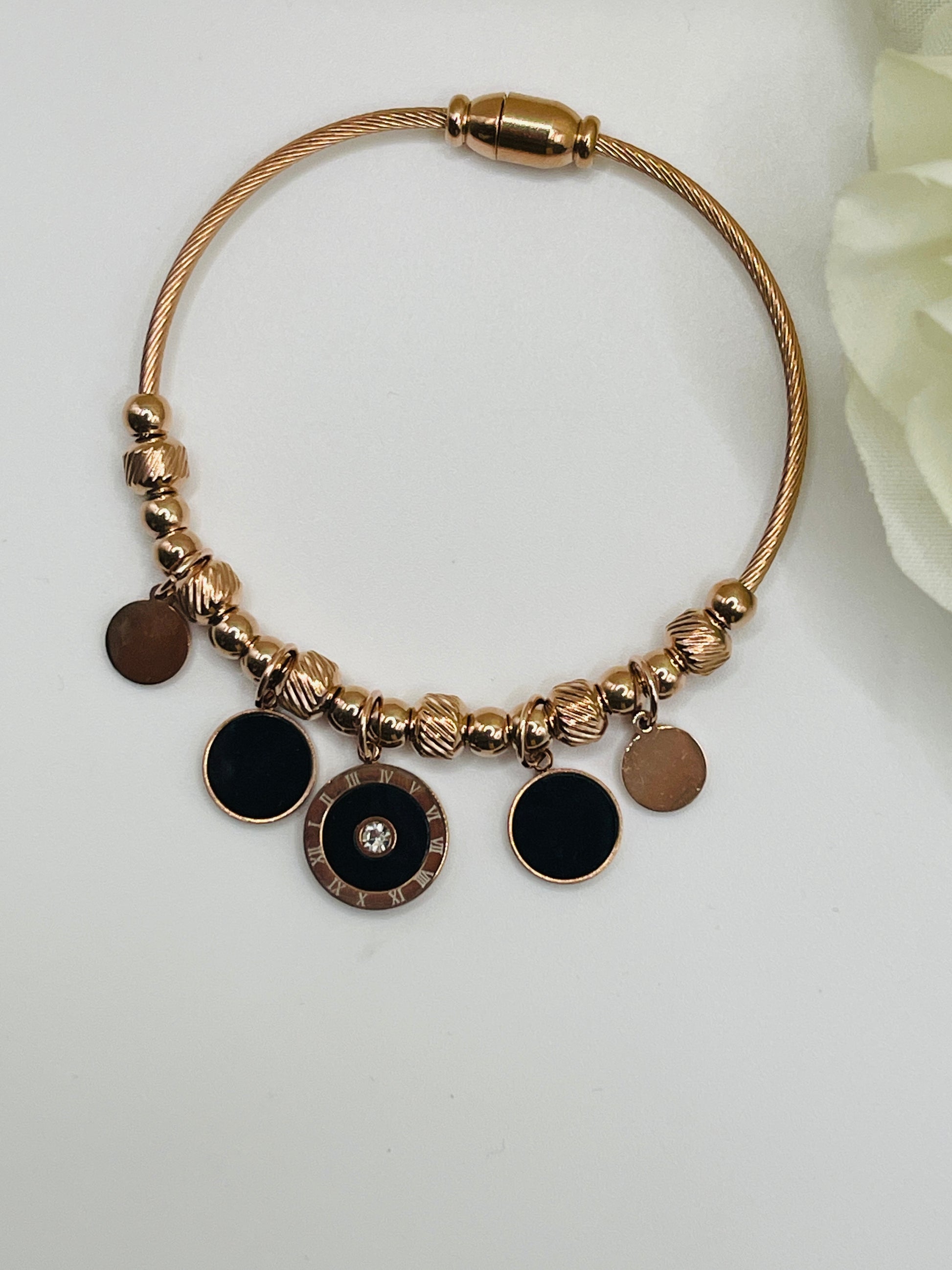 Rose Gold bracelet with black round charms on a white background