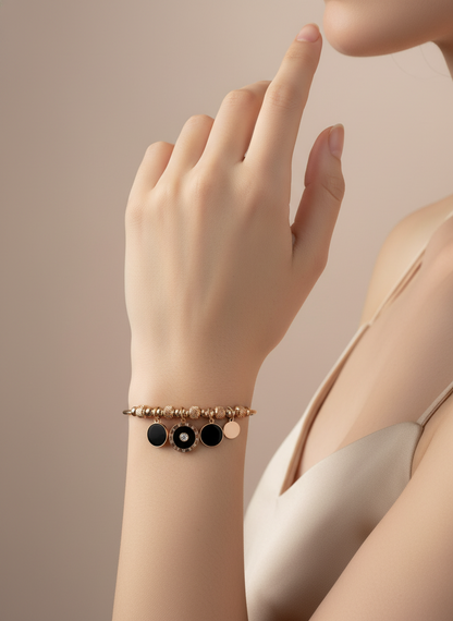 Hand wearing a bracelet with black and gold beads on a beige background