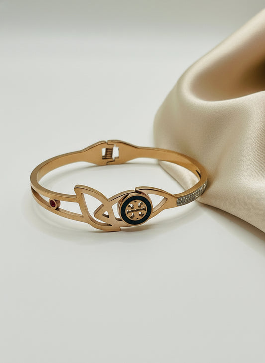 Rose gold bracelet with a central black circle design on a light background