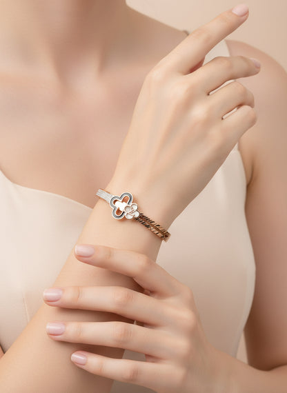 Rose gold bracelet with clover design on a white background with a rose.