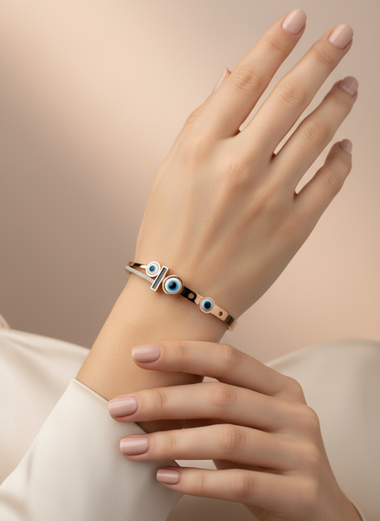 Hand wearing a bracelet with blue eye design on a neutral background