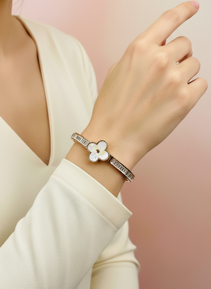 Hand wearing a rose gold bracelet with a floral design on a blurred background