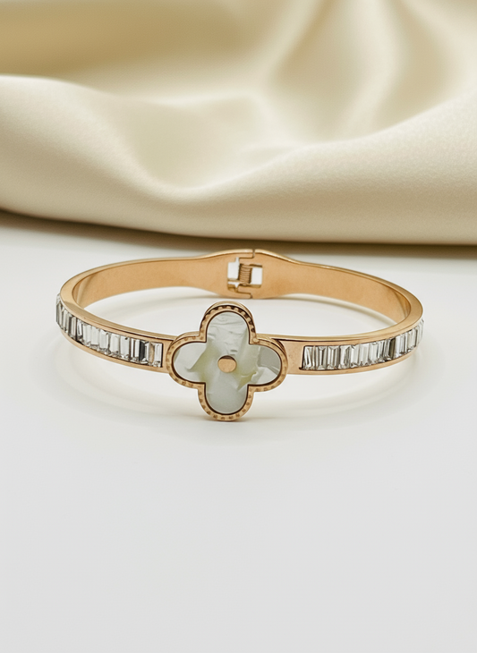 Rose Gold bracelet with a clover-shaped center and diamond accents on a beige fabric background