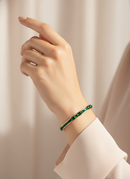 Hand wearing a Rose gold green stone bracelet on a plain background