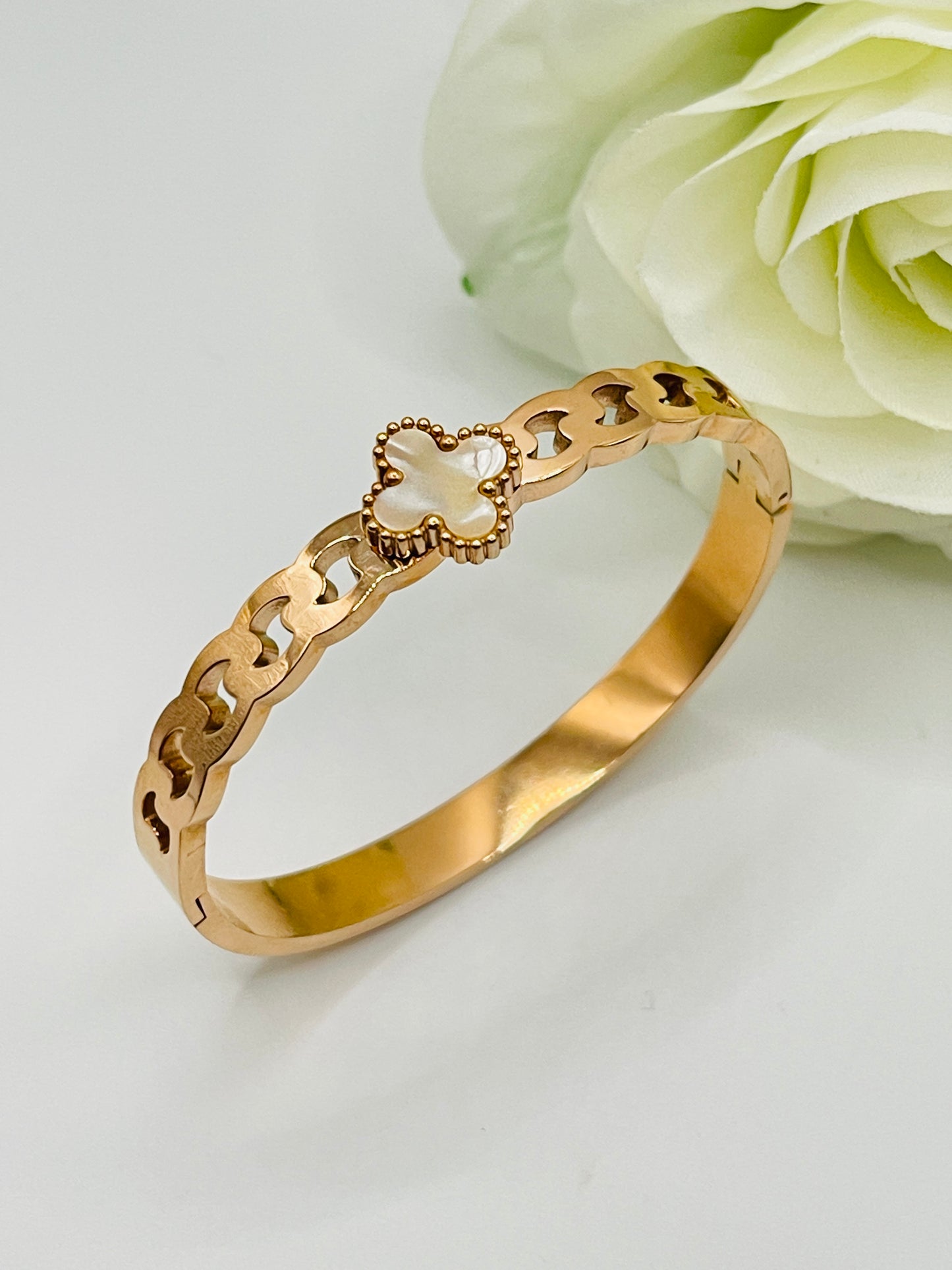 Gold bracelet with a heart-shaped clasp on a light background