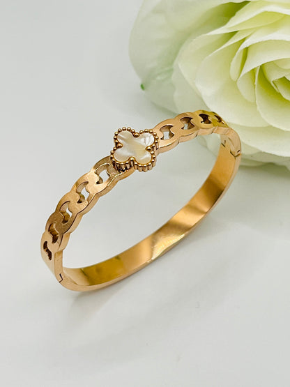 Gold bracelet with a heart-shaped clasp on a light background