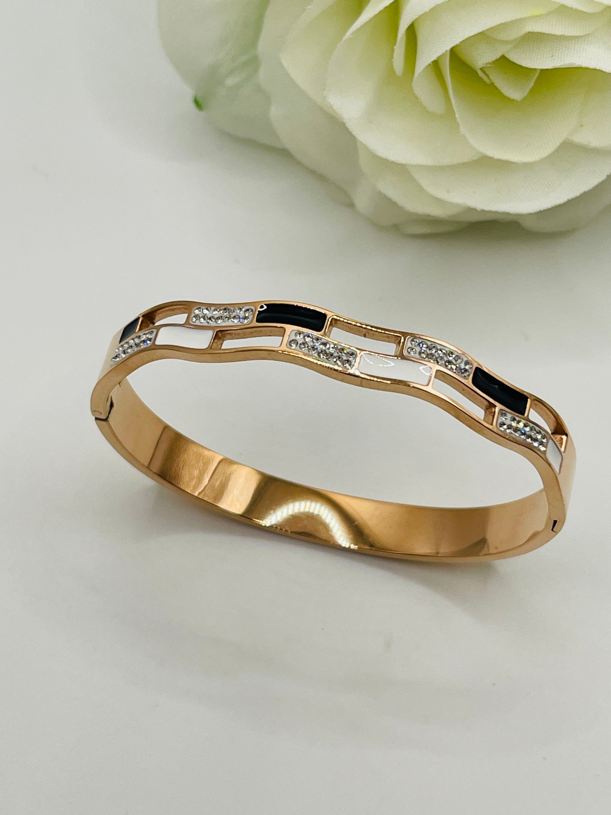 Gold bracelet with black and white stones on a light gray background