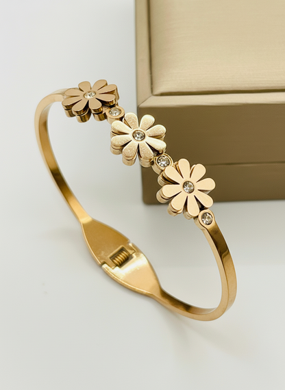 Rose gold bracelet with floral designs on a white surface
