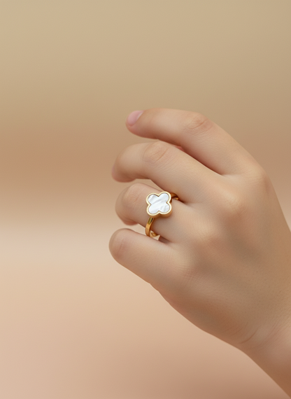 Gold ring with a clover design on a white stone surface
