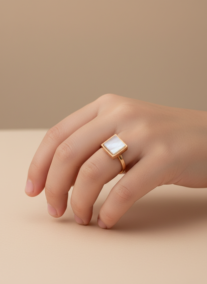 Gold ring with a square stone on a white surface