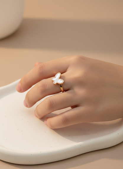 Hand wearing a butterfly-shaped rose gold kids ring on a neutral background
