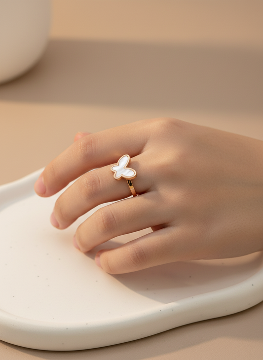 Hand wearing a butterfly-shaped rose gold kids ring on a neutral background