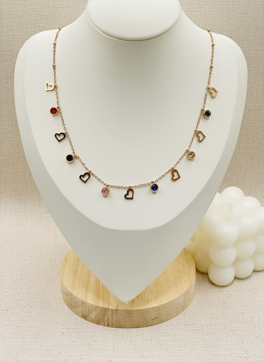 Necklace with heart-shaped charms on a mannequin bust with a ring beside it.