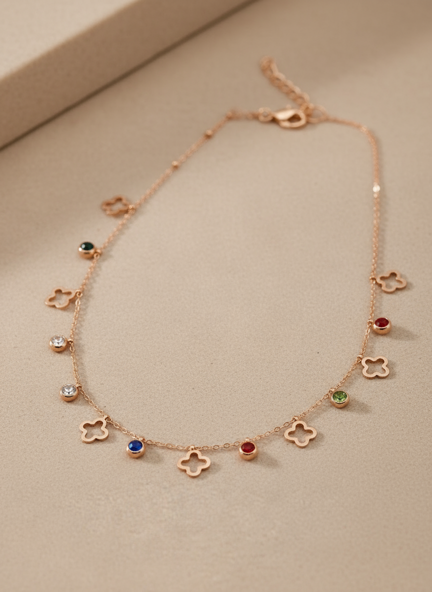 Rose gold necklace with floral and gemstone pendants on a beige background