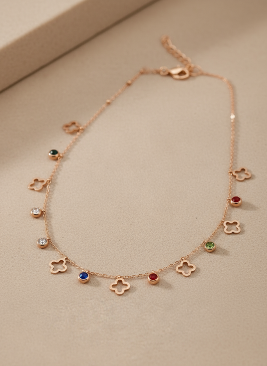 Rose gold necklace with floral and gemstone pendants on a beige background