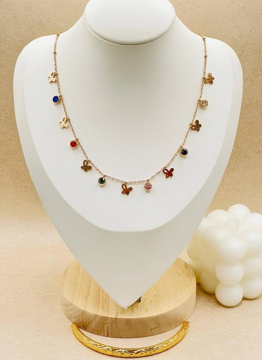 Necklace with colorful charms on a white mannequin bust with a gold base.