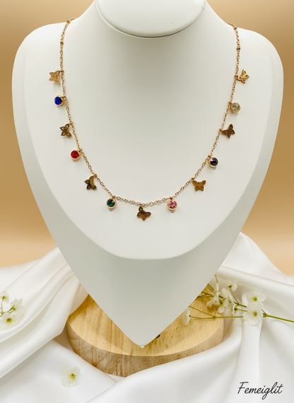 Necklace with colorful charms on a mannequin bust, accompanied by a ring on a small stand.