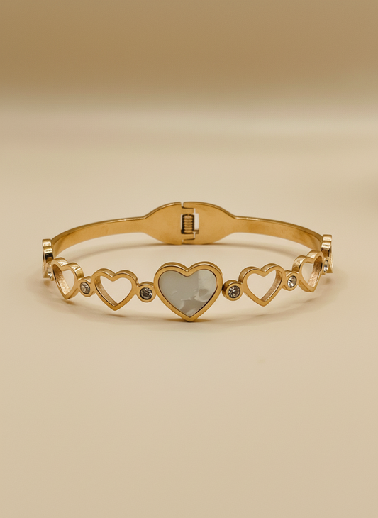 Gold bracelet with heart designs on a light gray background