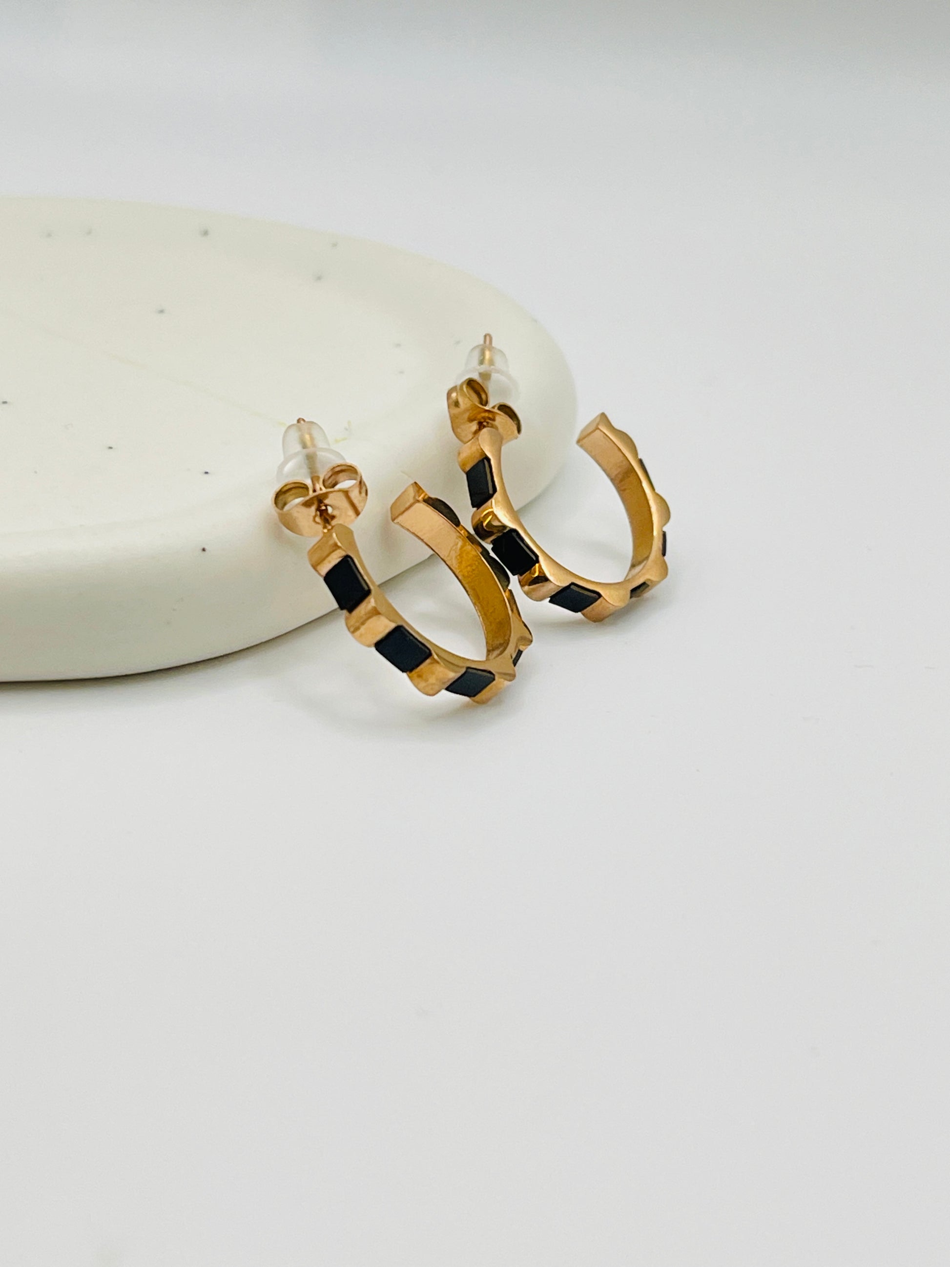 Rose Gold hoop earrings with black square pattern on a white surface