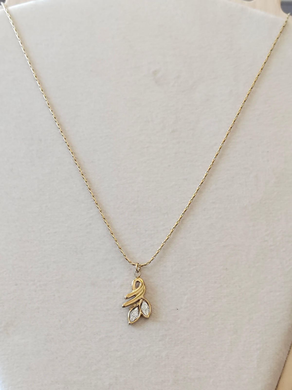 A delicate gold chain necklace with a small leaf-shaped pendant featuring a clear marquise gemstone, displayed on a cream-colored jewelry bust.