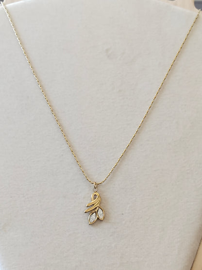 A delicate gold chain necklace with a small leaf-shaped pendant featuring a clear marquise gemstone, displayed on a cream-colored jewelry bust.