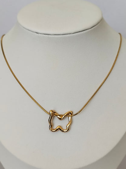 A gold necklace with an abstract, wavy open pendant displayed on a white fabric jewelry bust.