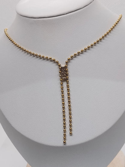 A gold-toned beaded necklace with a Y-shaped drop pendant, displayed on a white jewelry bust.