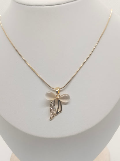 A delicate gold chain necklace with a bow and leaf pendant, displayed on a white jewelry bust. The bow is made of smooth, pale pinkish-white stones, while the leaf is gold with small clear rhinestones.