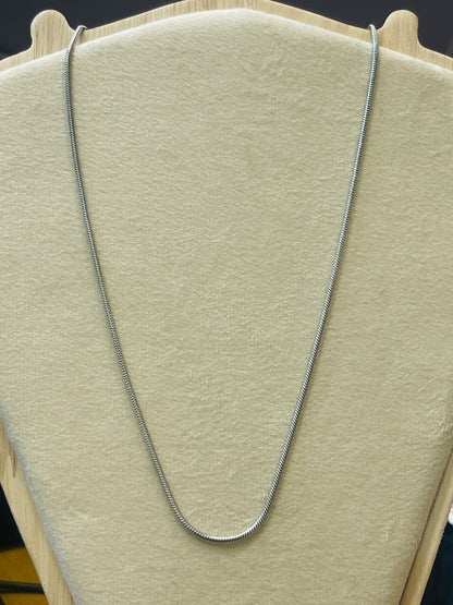 A silver snake chain necklace draped over a beige velvet jewelry display bust.