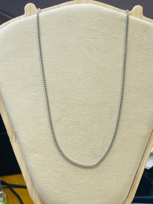 A silver-toned chain necklace draped over a beige fabric jewelry display bust.