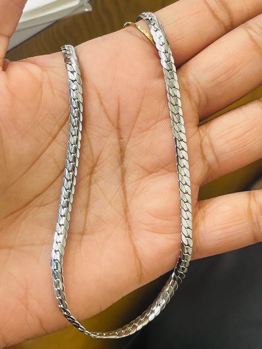 A silver-toned metal chain necklace with a textured, woven link design, draped over a person's hand.