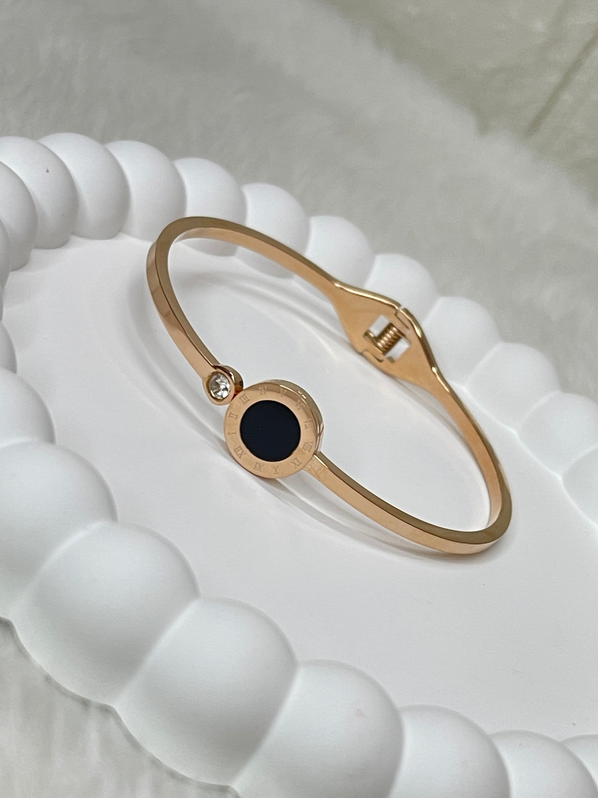 Rose Gold bracelet with a black gemstone on a white textured surface