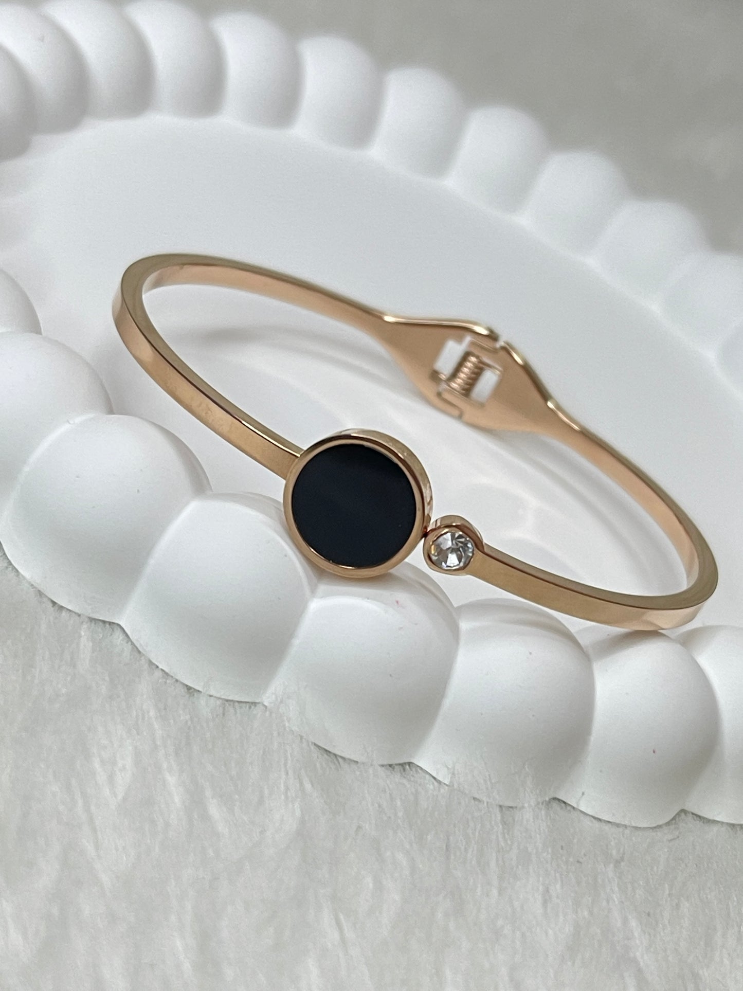 Rose Gold bracelet with a black center on a white textured surface