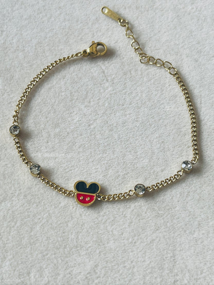 A gold chain bracelet featuring a Mickey Mouse head charm with red and blue enamel, accented by clear rhinestones on a textured white background.