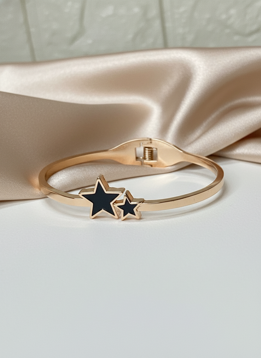 Rose gold bracelet with black star charms on a satin surface