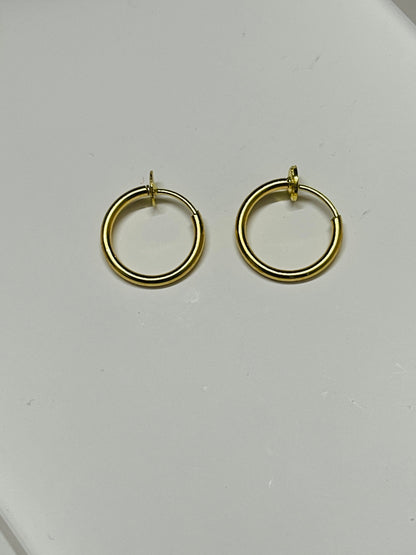 A pair of gold hoop earrings with a polished finish, displayed on a plain light gray surface.