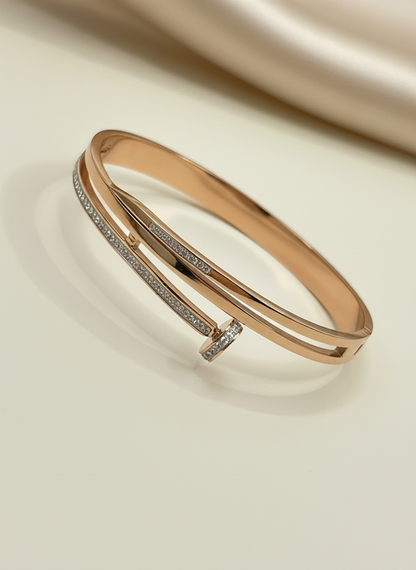 Rose gold bracelet with diamond accents on a beige fabric background