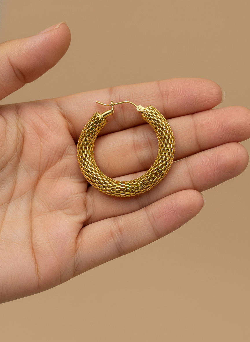 Gold hoop earrings on a white surface with a floral background