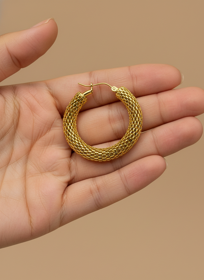 Gold hoop earrings on a white surface with a floral background