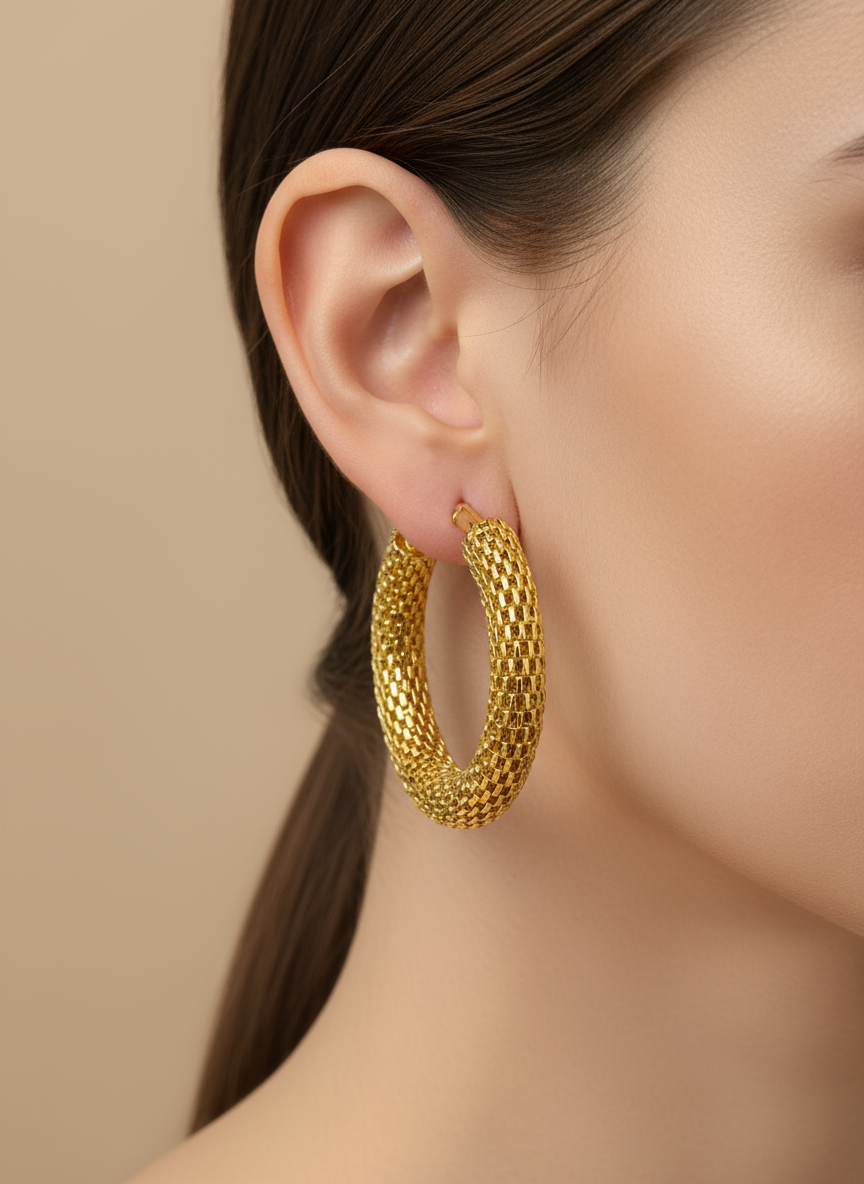Gold hoop earrings on a white surface with a floral background
