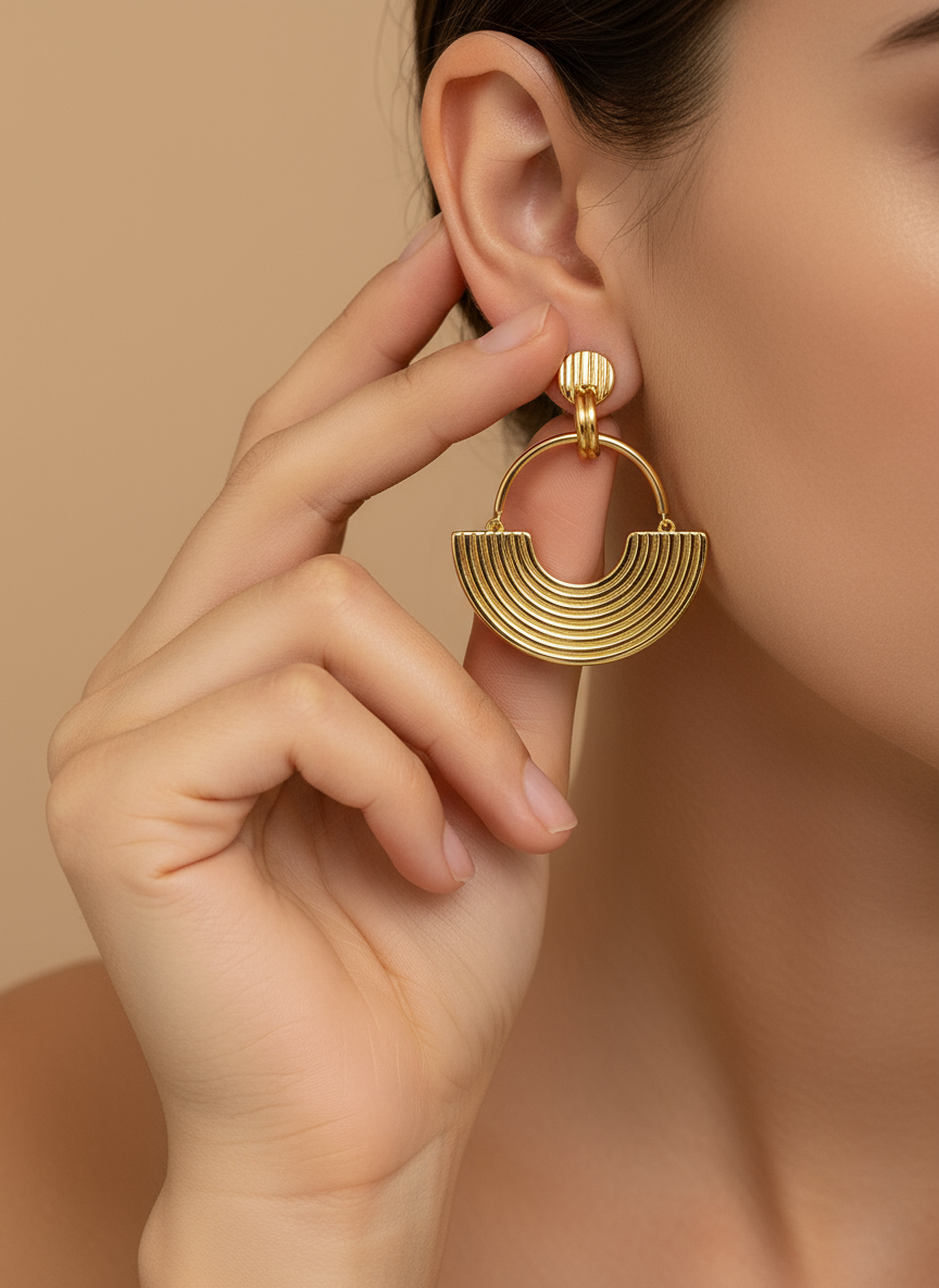 Gold hoop earrings on a white textured surface