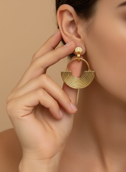 Gold hoop earrings on a white textured surface