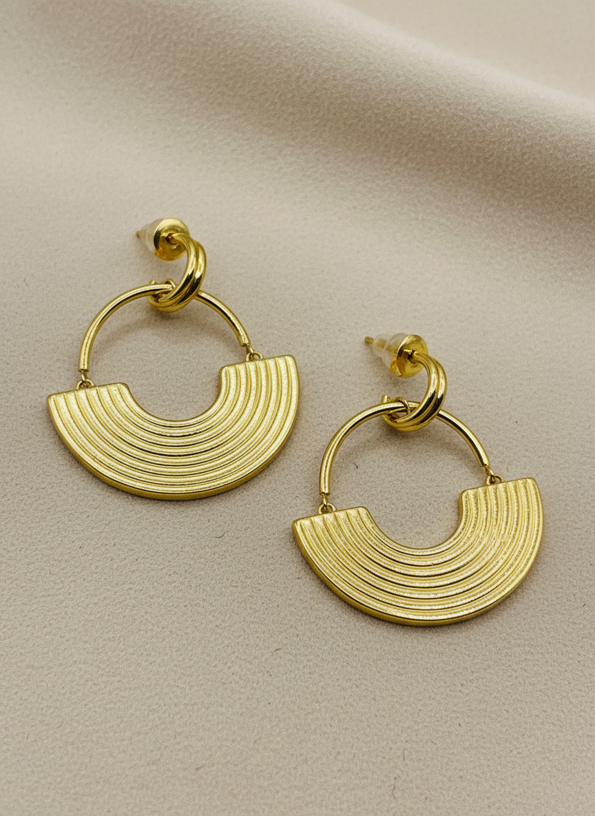 Gold hoop earrings on a white textured surface