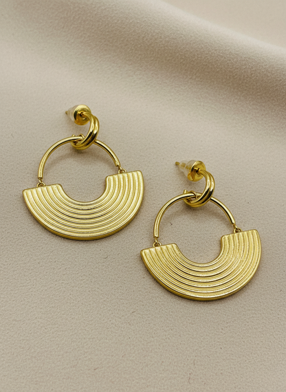 Gold hoop earrings on a white textured surface