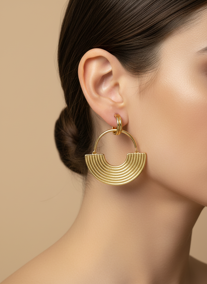 Gold hoop earrings on a white textured surface