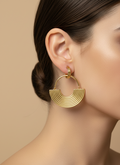 Gold hoop earrings on a white textured surface
