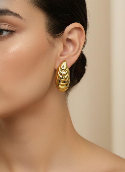Gold hoop earrings on a white surface with a floral background