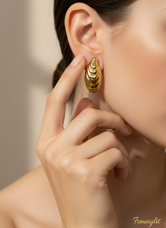 Gold hoop earrings on a white surface with a floral background